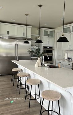 a kitchen with an island and four stools in front of the countertop area