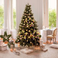 a decorated christmas tree sitting in the middle of a living room with presents on the floor