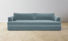 a blue couch sitting on top of a hard wood floor next to a white wall