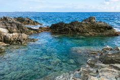 the water is crystal blue and there are rocks on the shore that look like they have been washed ashore