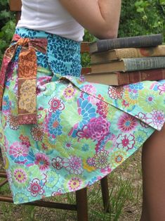 a woman is sitting on a chair wearing a colorful skirt and holding a book in her hand