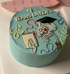 a blue cake decorated with an image of a person holding a book and graduation cap