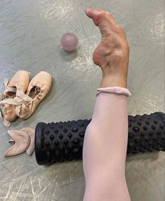 a person's arm and foot with ballet shoes on the floor