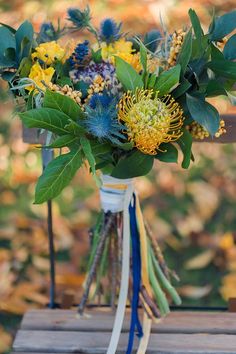 a bouquet of flowers sitting on top of a wooden table next to leaves and branches