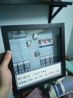 someone is holding up a video game frame with some earrings on it in front of a bed