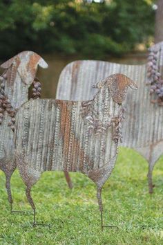 two metal sheep sculptures sitting in the grass