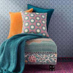 a couch with pillows and blankets on it in front of a wallpapered background