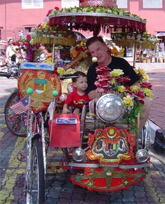 a man riding on the back of a motorcycle with a small child in it's seat