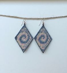 a pair of blue and pink beaded earrings hanging from a string on a white surface