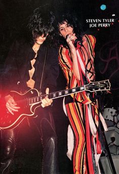 two people standing next to each other holding guitars