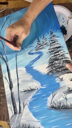 someone is painting a snowy scene on a paper plate