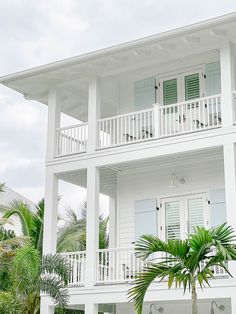 a white house with two balconies and palm trees