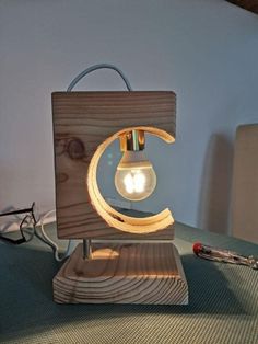 a wooden lamp with a light bulb in the shape of a crescent on top of it