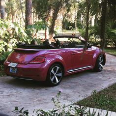 a red convertible car parked in front of some trees