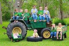 a group of children sitting on the back of a green tractor with two large tires