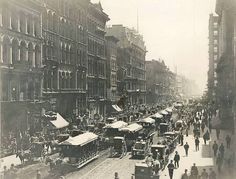 an old black and white photo of people walking down the street