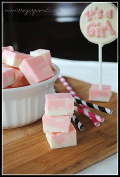 pink and white marshmallows in a bowl on a cutting board with striped strawberries