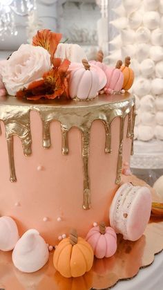 there is a pink cake with gold icing on the top and decorations around it