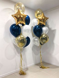 two large balloons with gold and white stars are on the floor in front of a wall