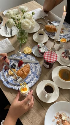 people eating breakfast at a table with cups and saucers