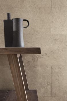 two vases sitting on top of a wooden table in front of a tiled wall