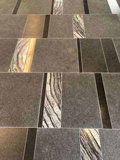 the floor is made up of grey and black marble tiles with gold lines on them