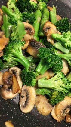 broccoli and mushrooms are being cooked in a wok