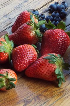 strawberries and blueberries on a wooden table