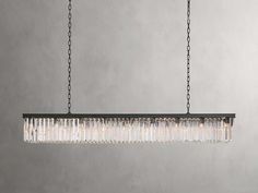 a rectangular chandelier hanging from a chain on a gray wall in an empty room