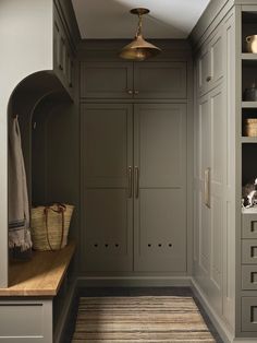 a hallway with gray cabinets and wooden flooring next to a shelf filled with items