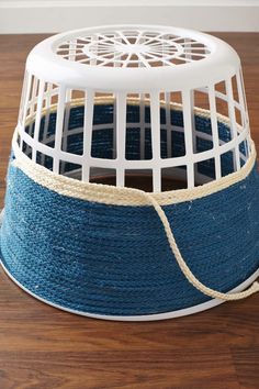 a white bird cage sitting on top of a wooden floor next to a blue rope