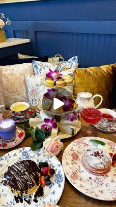 a table topped with plates and cakes covered in frosting next to cups and saucers