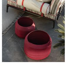 two red baskets sitting on the ground next to a couch