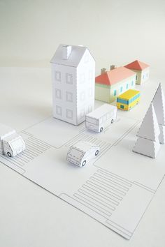 some paper houses and cars on a white surface