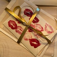 two envelopes wrapped in gold ribbon and decorated with red lipstick prints