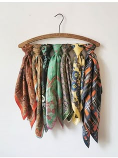 an assortment of scarves hanging from a wooden hanger