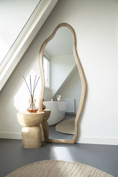 a mirror sitting on top of a wooden table next to a vase