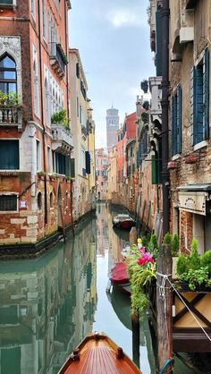 a boat traveling down a canal next to tall buildings and flowers on the railings