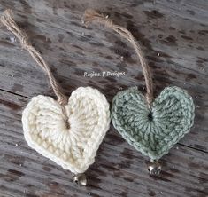 two crocheted heart ornaments hanging from twine on wooden planks with rope