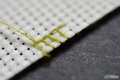 a close up view of a piece of white fabric with yellow thread on it and some black dots