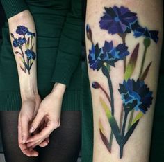 two women with matching tattoos on their arms holding each other's hands, one has blue flowers and the other has green leaves