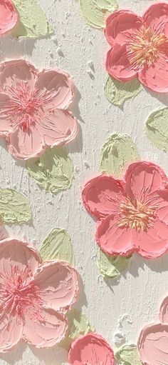 some pink flowers and green leaves on a white surface