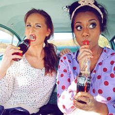 two women sitting in the back of a car drinking soda