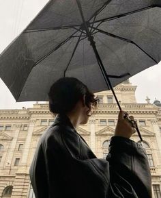 a woman holding an umbrella in front of a building