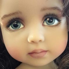 a close up of a doll's face with blue eyes