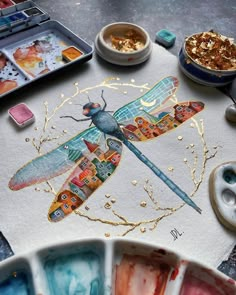 a dragonfly painted on paper next to other paints