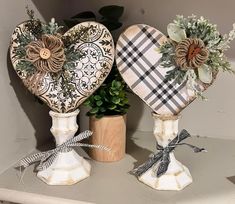 two decorative heart shaped vases sitting on top of a shelf next to a potted plant