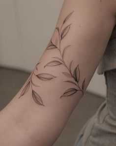 a woman with a tattoo on her arm that has leaves coming out of the top