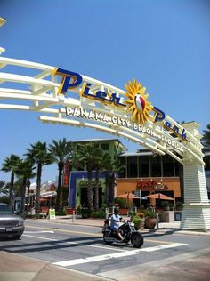 a person riding a motorcycle under a sign that says play park on the side of a road