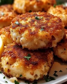 some crab cakes on a white plate with lemon wedges